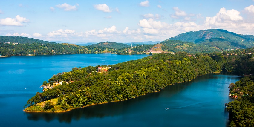 Umian Lake viewpoint with a large water body of the lake, mountains and tall green trees.