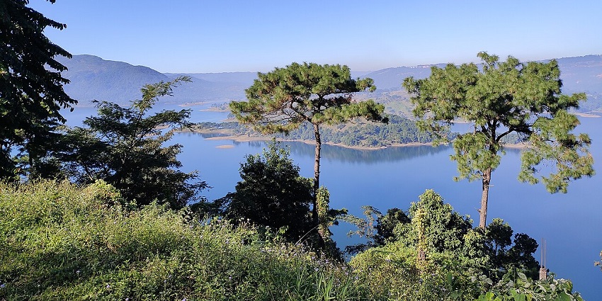 Umiam viewpoint with a large water body of the dam, distant buildings and hills.
