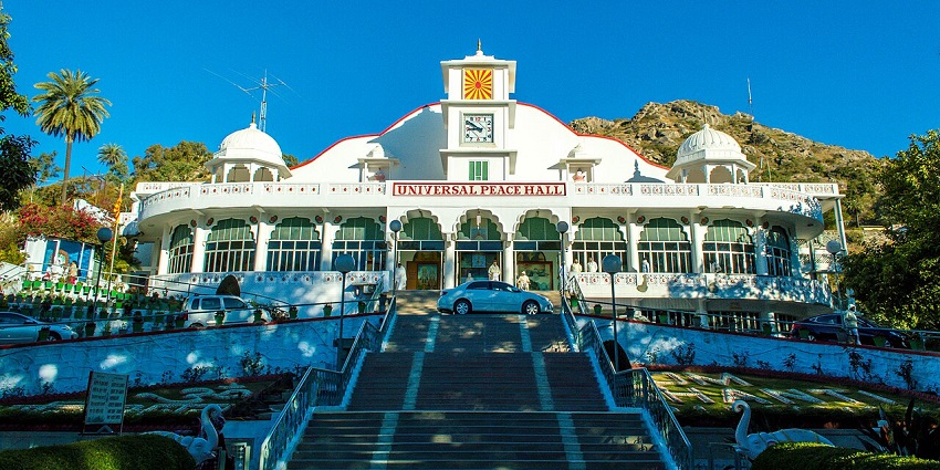 Universal Peace Hall at Mount Abu with its white architectural building and a car parked.