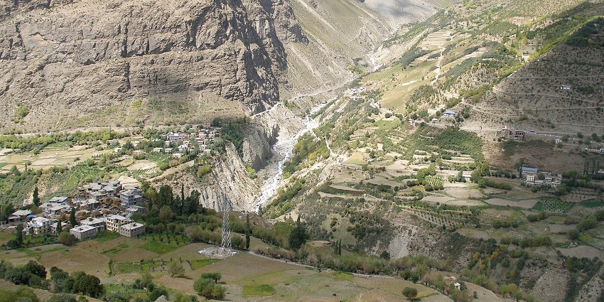 Terraced green fields and scattered village homes nestled in a deep mountain valley, amongst the things to do in Lahaul and Spiti.