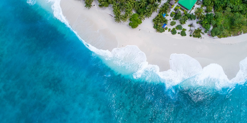 Daytime view of the sandy beach and clear blue waters of Vaadhoo Island, Maldives.