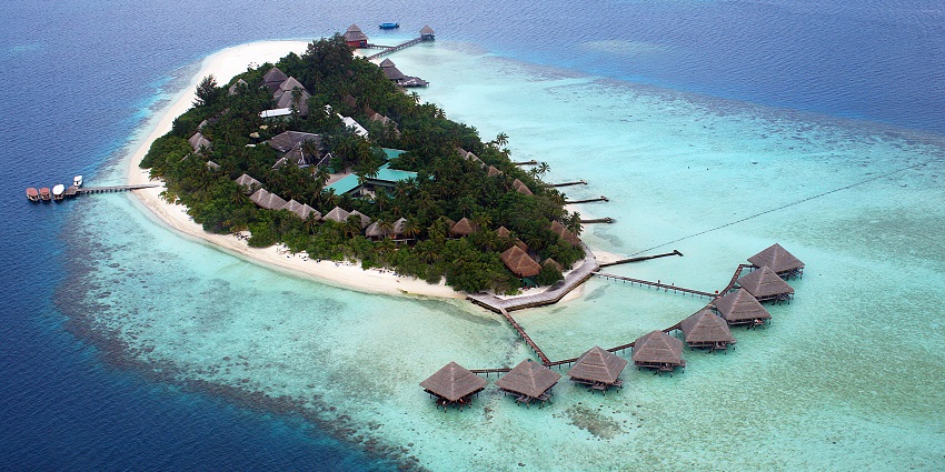 Aerial view of a tropical island resort with overwater bungalows surrounded by clear turquoise water, one of the islands in Maldives.