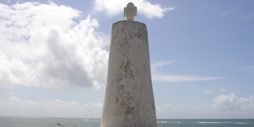 People sitting around the Vasco da Gama Pillar with a blue river view in the background.