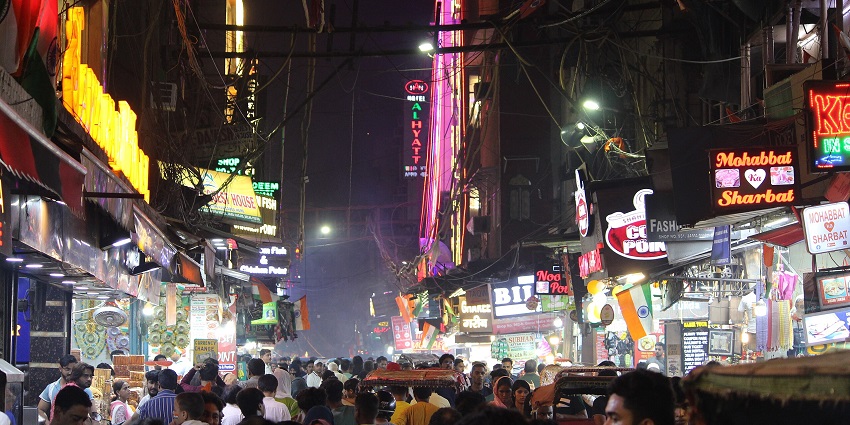 Bustling night market in Delhi with vibrant lights, street food, and lively stalls.