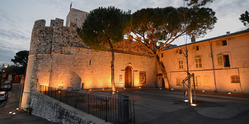 Stone museum tower among trees, perched above Cannes, offering panoramic coastal views.
