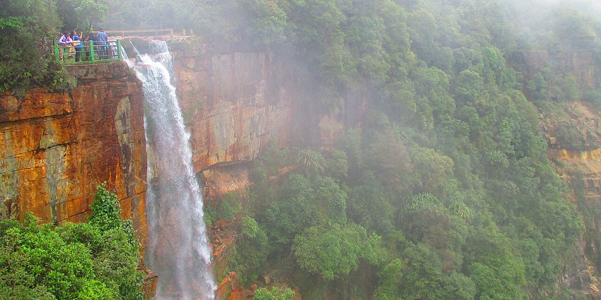 Wah Kaba falls with people standing on the viewpoint on a cliff and water flowing.