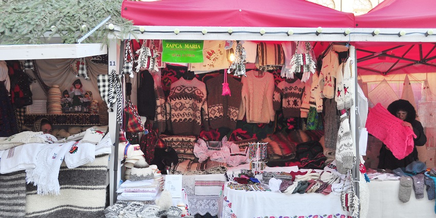 Woolen sweaters, handmade crafts, and traditional textiles displayed at a vibrant stall