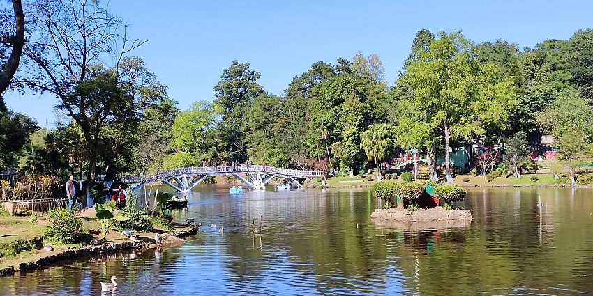 Ward’s Lake in Shillong with ducks on the lake, people standing and boats on the lake.