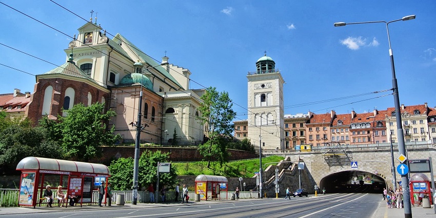 A road of warsaw old town with people sitting at the bus stop and buildings of the town