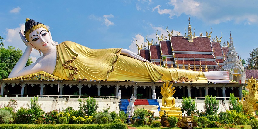 Golden reclining Buddha statue at Wat Pho temple, Bangkok, displaying detailed Thai temple carvings.