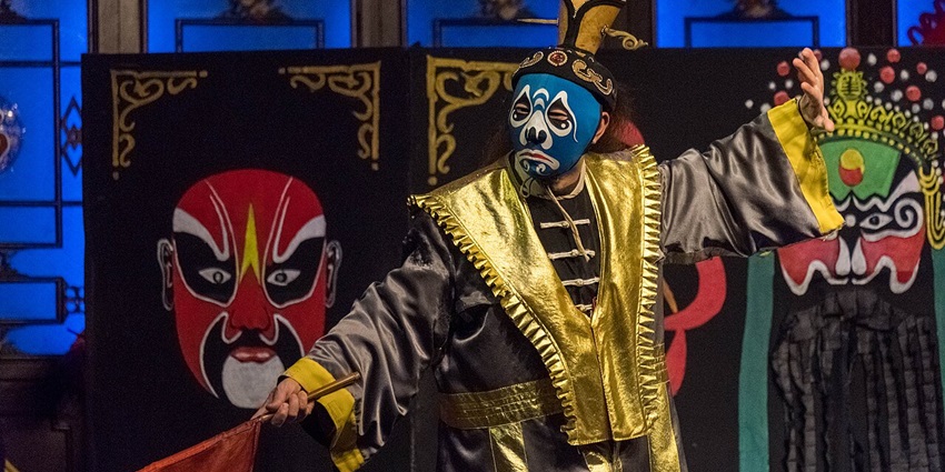 A Sichuan opera performer mid-act as they dramatically change face masks in a traditional theatre.