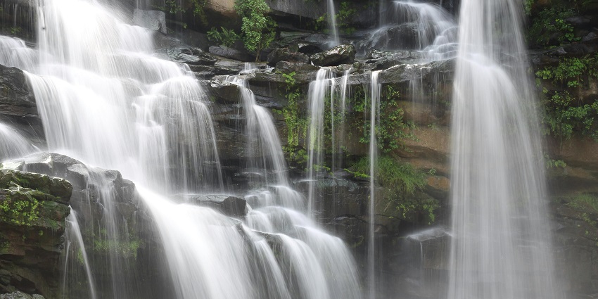An image of Waterfall Bluff, Pondoland with water flowing on the rocky surface and small grass on the rocks, one of the top hidden places in South Africa.
