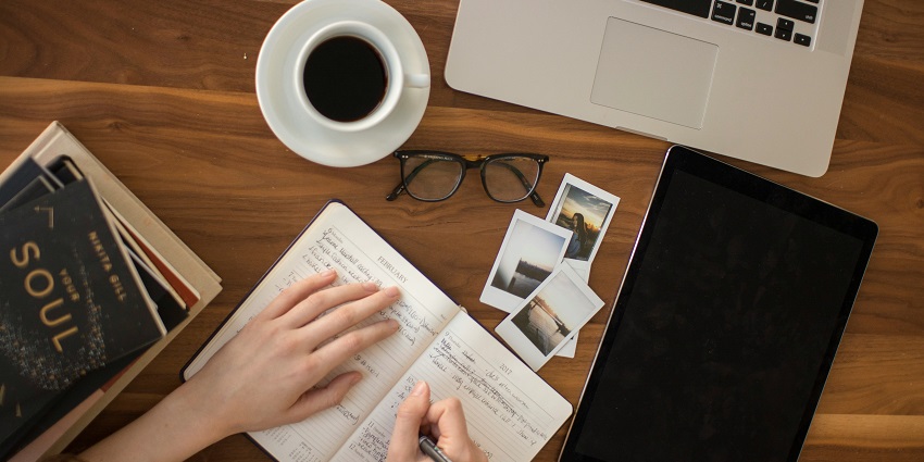 Person writing in a notebook with a ballpoint pen, focusing on thoughtful planning.