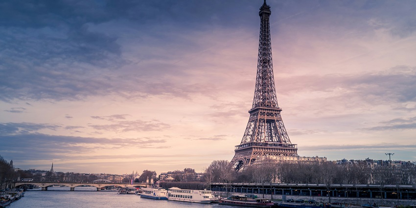 Eiffel Tower in Paris standing tall with soft lighting and trees in the foreground.