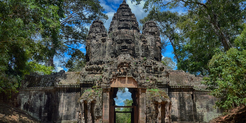 Ancient stone temple entrance surrounded by jungle trees and moss-covered structures