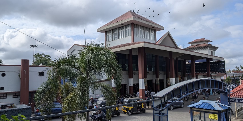 Front view of Thrissur Railway Station with passengers and parked vehicles