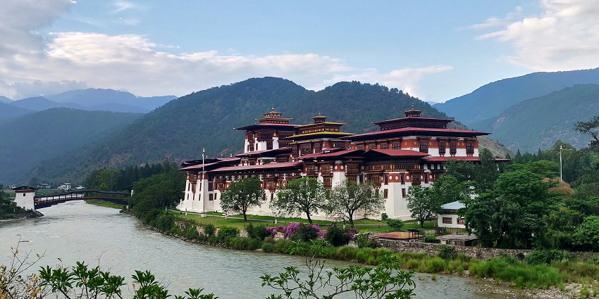 Peaceful Bhutanese monastery by a lake reflecting why Is Bhutan Worth Visiting today.