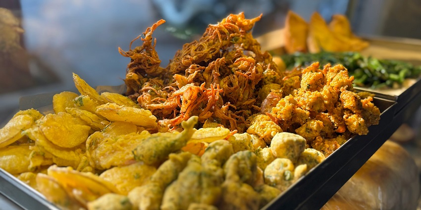 Image of colorful street food stalls with a variety of local snacks displayed in an open market setting.