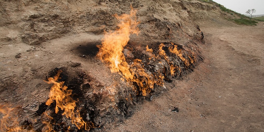 A natural fire blazing from a hillside, fed by underground gas vents, burning brightly even in daylight.