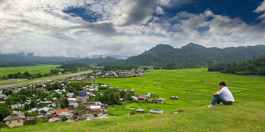 Ziro Valley with Ziro town at a distance and buildings, a person sitting and green hills