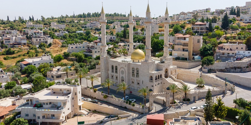 Abu Ghosh with a unique structure with four pillars standing in the middle, surrounded by buildings.