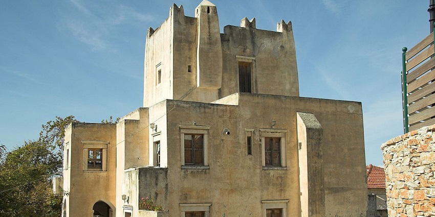 The Barozzi tower in Naxos with a traditional Greek architectural building and multiple closed windows.