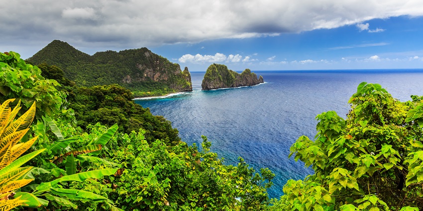 Aerial view of Pago Pago town surrounded by lush green mountains and calm harbor waters.