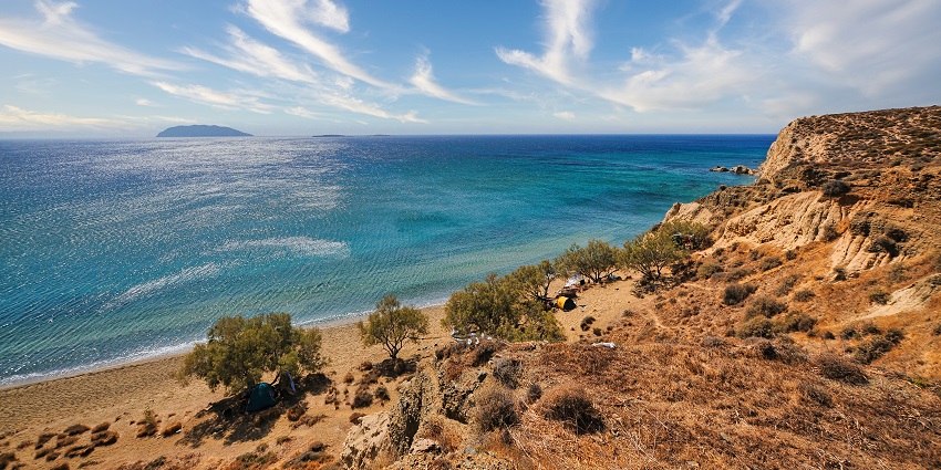 Roukounas Beach with calm waves and golden sand, peaceful places to visit near Santorini.