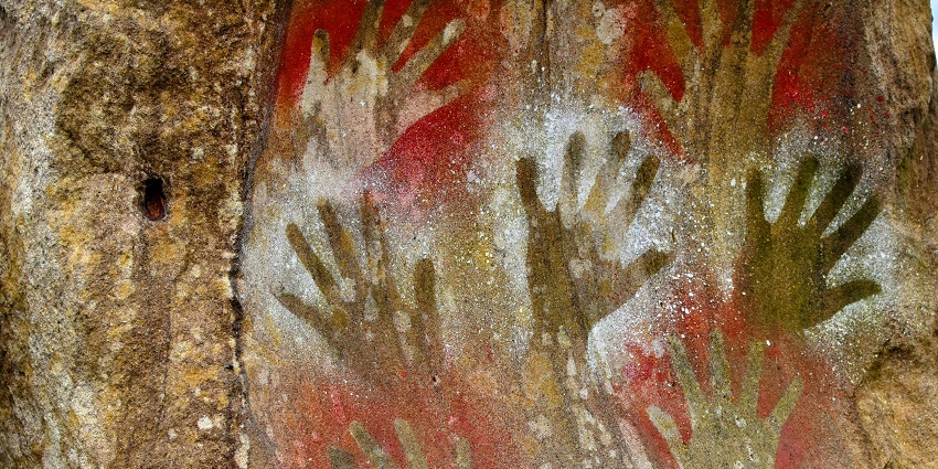 Ancient cave paintings of hands using a red pigment found on the walls of a cave.