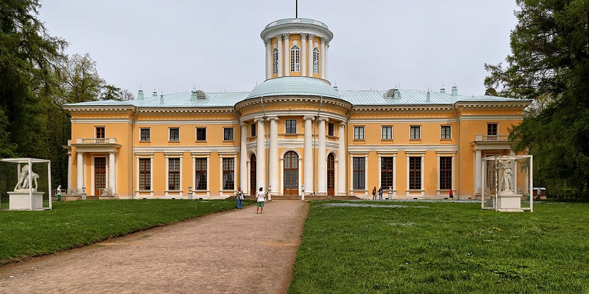 Neoclassical mansion with sculpted gardens, a tree-lined avenue, and few visitors around.