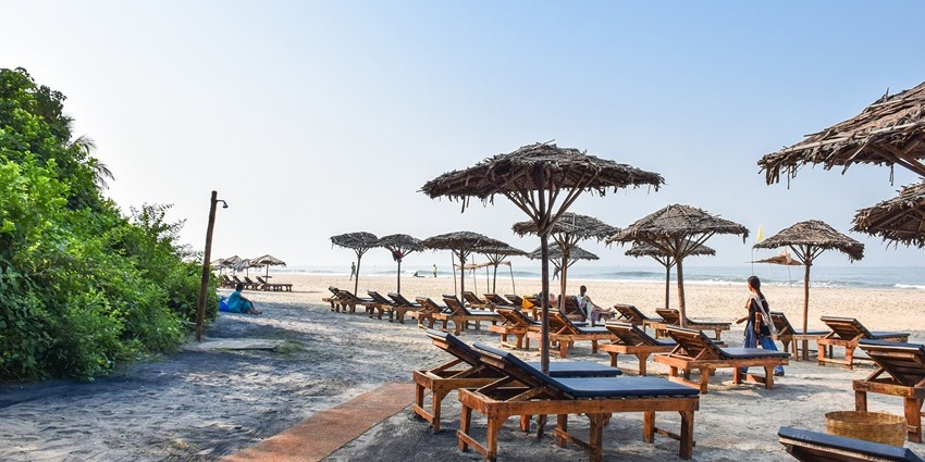 Ashwem Beach in Goa with lounge chairs, a sandy shoreline, and a calm, relaxing atmosphere.