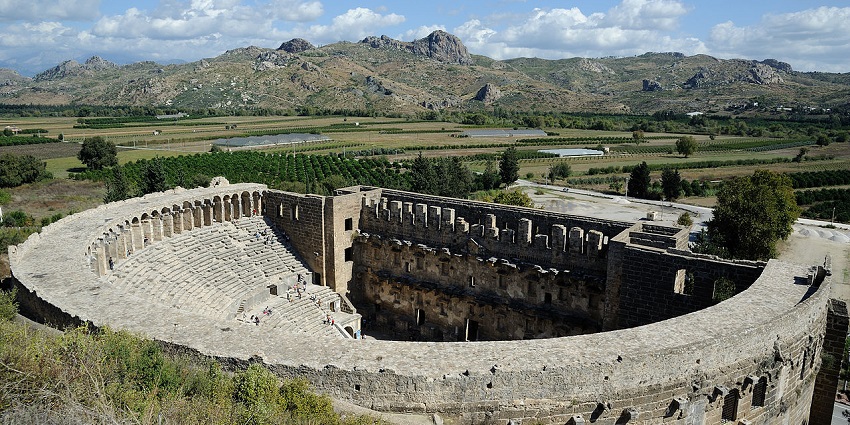 Roman amphitheatre at Aspendos with grand stone arches and semicircular tiered seating.