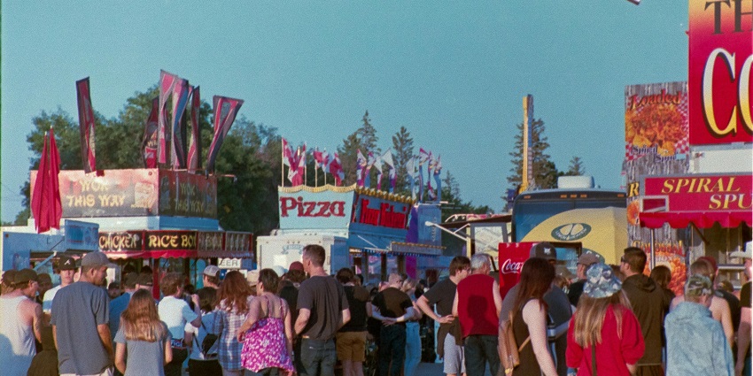 Attending a lively summer festival with people, stalls, and open-air entertainment.