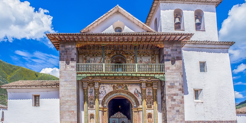Outside the church of Iglesia San Pedro Apóstol in Peru, with a colourful entrance gate.