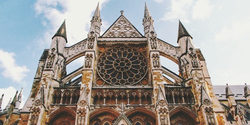 The exterior of Westminster Abbey with Gothic architecture and grand arched entrance on a clear day.