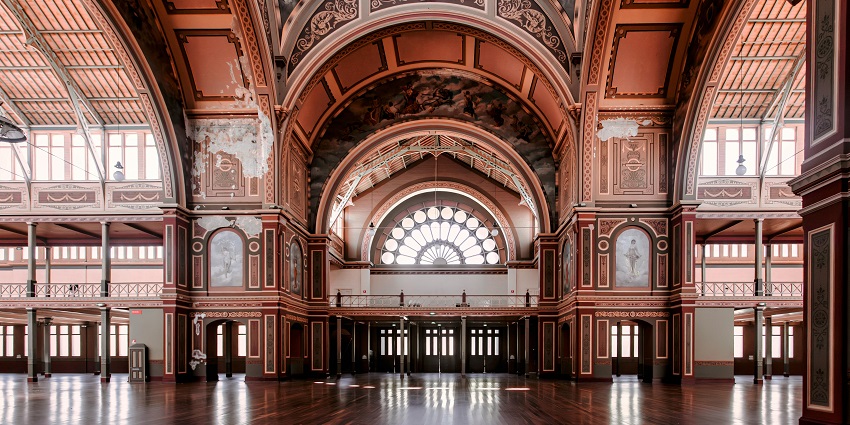 Interior of the Victoria Hall with multiple unique windows, hanging lights and detailed architecture.
