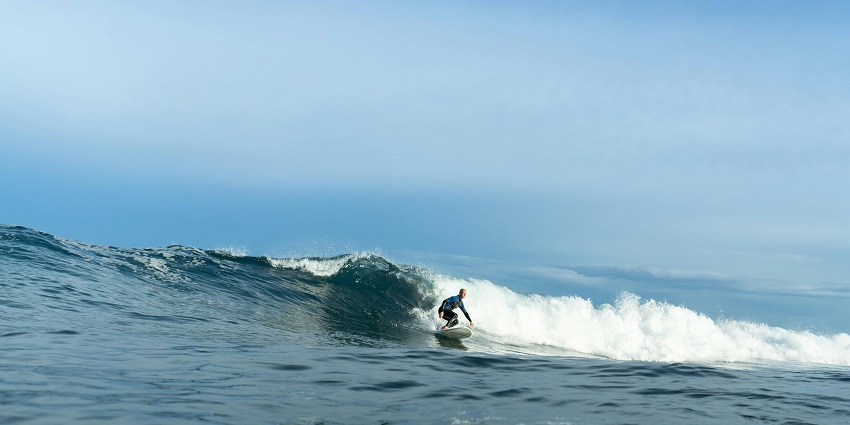 Surfer riding high waves at Bathsheba’s Soup Bowl—top things to do on Barbados in December.
