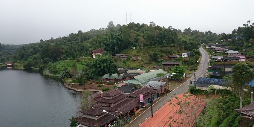 Lakeside House in Ban Rak Thai faces still water, surrounded by misty hills and greenery.