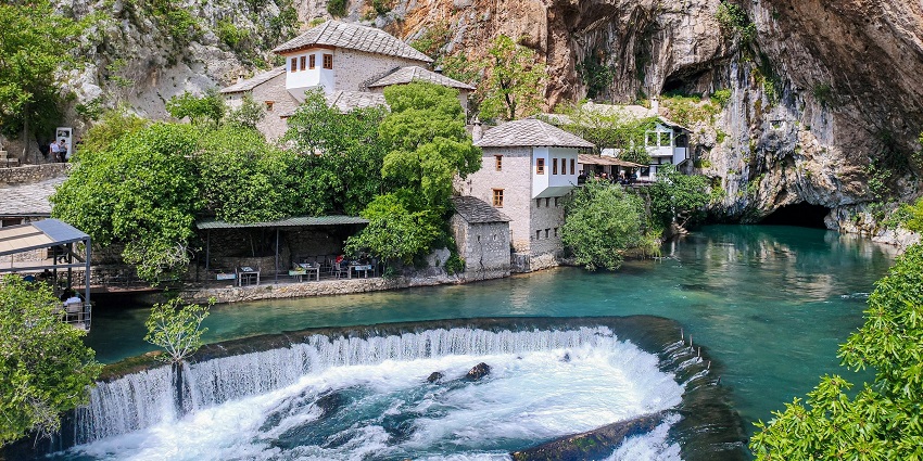 Buna Spring and historic Dervish tekke in Blagaj are surrounded by cliffs and clear water.