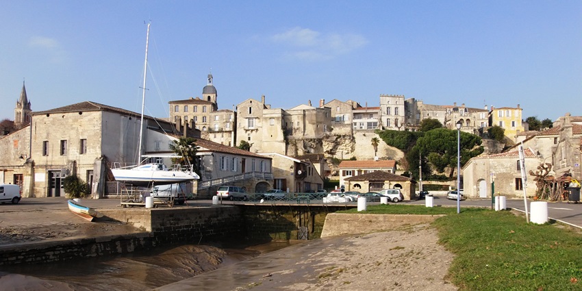 Historic stone buildings and a hilltop town overlooking a quiet waterfront, amongst the top places to visit near Bordeaux.