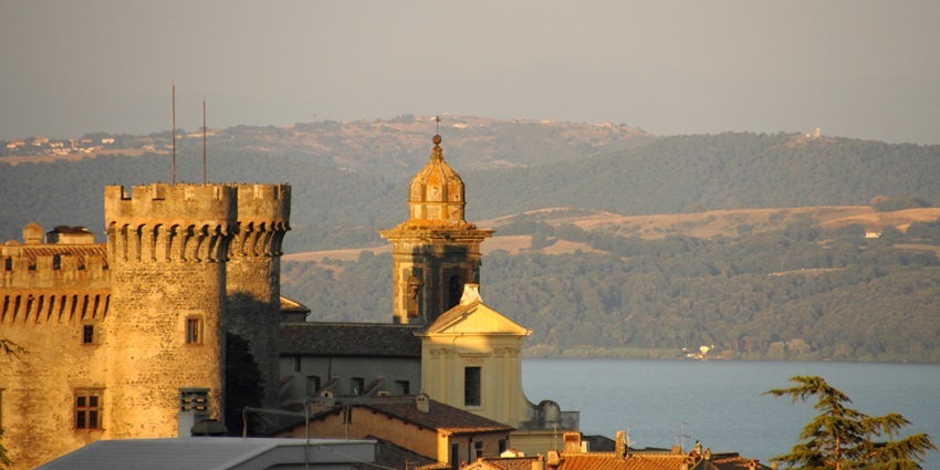 Castel Orsini Odescalchi in Bracciano with traditional Roman architecture and a distant lake.
