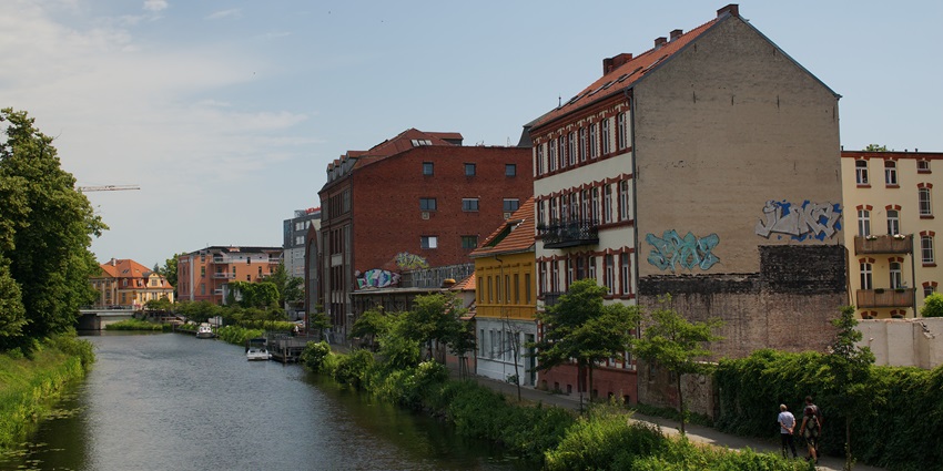 Riverside path lined with trees and colourful buildings in Brandenburg an der Havel.