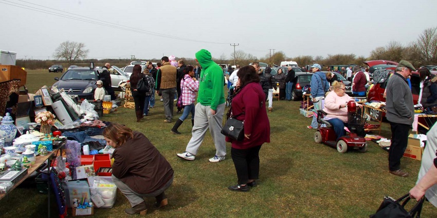 People browsing through stalls at an outdoor market on a sunny day – Kessingland car boot sale.
