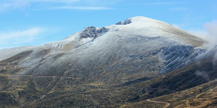 A vast mountain landscape with a snow-covered peak under a blue sky and scattered clouds, one of the places to visit near Istanbul.