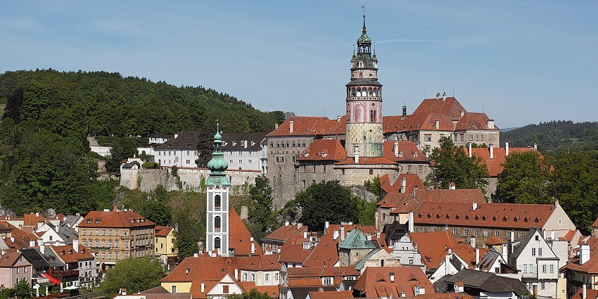 Historic hilltop castle and church tower above red-roofed town, one of the places to visit near Prague.