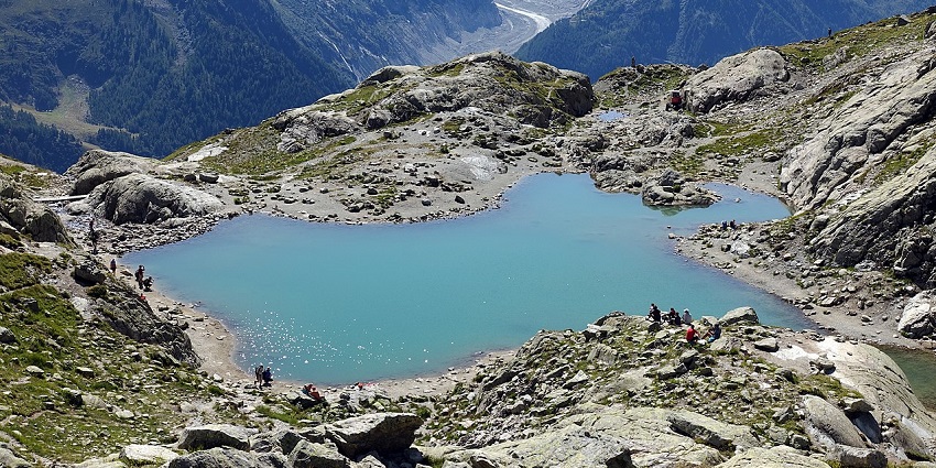 Heart-shaped alpine lake with turquoise waters surrounded by rocky terrain and glaciers.