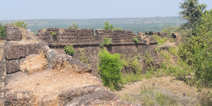 Historic Chapora Fort with broken walls and ruins surrounded by greenery in Goa.