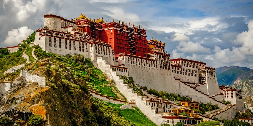 Potala Palace in Lhasa, Tibet, is a majestic historic structure set against a mountainous backdrop.
