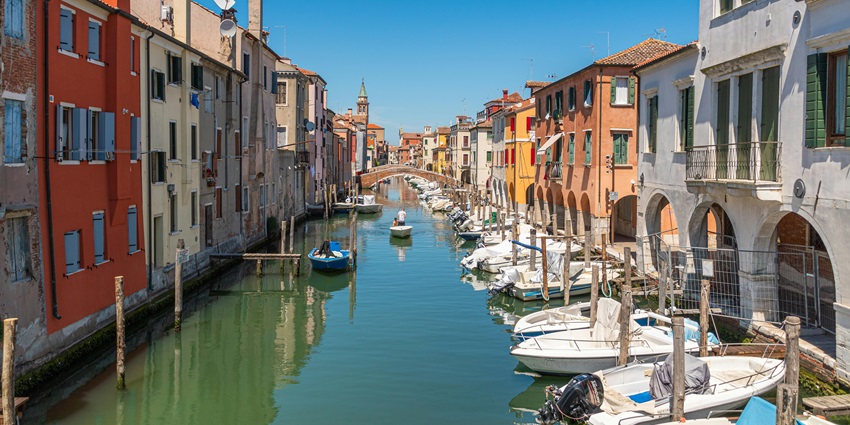 Chioggia in Italy, with a small water body of a canal, multiple boats and vibrant buildings, one of the places to visit near Venice.