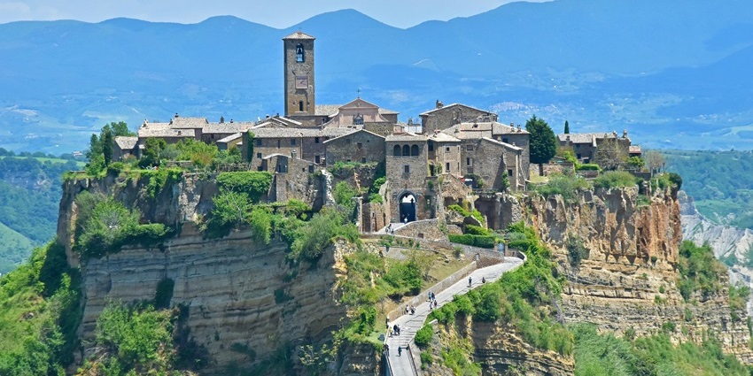 People walking up the hill on a long pedestrian bridge leading to Civita di Bagnoregio.